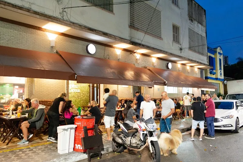 Movimento à noite na frente do Grill II, com mesas cheias e luzes do toldo
